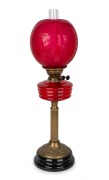 Antique style oil lamp with ruby glass font and shade, black button burner on brass column and black ceramic base, 20th century, 67cm high.