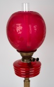 Antique style oil lamp with ruby glass font and shade, black button burner on brass column and black ceramic base, 20th century, 67cm high. - 2