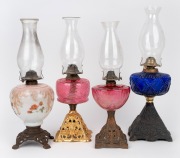 Four antique oil lamps with coloured glass fonts and cast metal bases, 19th/20th century, ​​​​​​​the largest 53cm high.