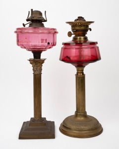Two oil lamps with ruby glass fonts, brass burners and bases, (incomplete), 20th century, 45cm and 47cm high.