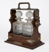 An antique English oak two bottle tantalus, housing two cut crystal decanters, 19th/20th century, 31cm high.