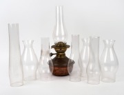 An antique copper and brass oil lamp with black button double burner and eight assorted glass chimneys, 19th/20th century.