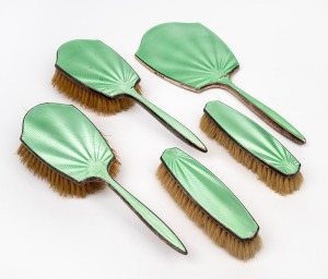 Five pieces of vintage sterling silver and green enamel vanity ware, comprising of a hand-mirror and four brushes, 20th century, the mirror 28cm high.