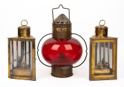 A pair of triangular brass oil lanterns; together with a red glass oil lantern, 20th century, (3 items), 34cm and 42cm high.