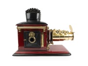 Large c. 1890s mahogany and brass MAGIC LANTERN with impressive triple-extension lens, tin chimney element, two side-opening doors with blue glass peepholes, and finely carved base; later retrofitted for electricity, dimensions approx. 46 x 30 x 64cm. - 2