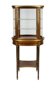 An attractive antique French mahogany display cabinet of oval form, with shelf base and adorned with ormolu mounts, circa 1880, 153cm high, 71cm wide, 42cm deep.