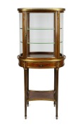 An attractive antique French mahogany display cabinet of oval form, with shelf base and adorned with ormolu mounts, circa 1880, 153cm high, 71cm wide, 42cm deep.