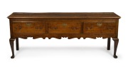 A Georgian oak three drawer Welsh dresser base with cabriole legs, original brass escutcheons and swan neck handles, circa 1760s, 79cm high, 203cm wide, 47cm deep. PROVENANCE: Purchased by the vendor from John Dunn Antiques in 1999 for $23,000. Purchase 