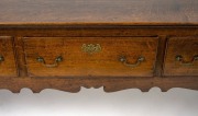 A Georgian oak three drawer Welsh dresser base with cabriole legs, original brass escutcheons and swan neck handles, circa 1760s, 79cm high, 203cm wide, 47cm deep. PROVENANCE: Purchased by the vendor from John Dunn Antiques in 1999 for $23,000. Purchase - 2