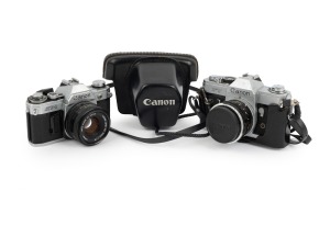 CANON: Pair of 1960s SLRs, comprising Canon FT QL (FL 50mm f1.8, with cap and leather case) and Canon AT-1 (FD 50mm f1.8). (2 items)