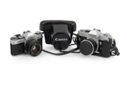 CANON: Pair of 1960s SLRs, comprising Canon FT QL (FL 50mm f1.8, with cap and leather case) and Canon AT-1 (FD 50mm f1.8). (2 items)
