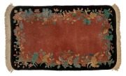 A Chinese Art Deco floral pattern wool rug on black and pink ground, 164 x 92cm.