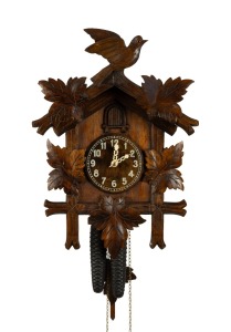A vintage German Black Forest cuckoo wall clock in carved linden wood case adorned with vine leaf and cuckoo decoration, printed Arabic numeral dial and fancy fretted and carved bone hands, 30 hour brass plate movement with coil gong strike, mid 20th century, 44cm high, 31cm wide.
