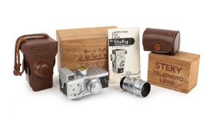 RIKEN OPTICAL: Steky IIIA subminiature camera [#9994], c. 1952, with Stekinar 25mm f3.5 lens, cap, yellow filter, and leather casing; offered together with Steky-Tele lens in leather case; both items in matching wooden boxes. (2 items)
