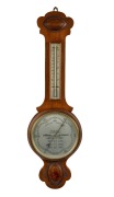 An antique English aneroid wheel barometer with mercury thermometer, the main dial with weather indications, housed in a walnut case, early 20th century, 81cm high.