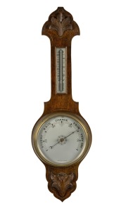 An antique English aneroid wheel barometer with mercury thermometer in carved oak case, early 20th century, 80cm high.