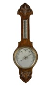 An antique English aneroid wheel barometer with mercury thermometer in carved oak case, early 20th century, 80cm high.