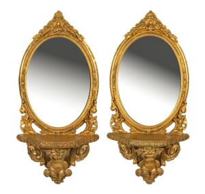A pair of vintage Italian gilt framed mirrored wall brackets with cupid decorations, 20th century, 66 x 30cm each overall.
