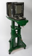 Circa 1920s large format studio camera, plate dimensions 21 x 16.5cm, Taylor Taylor & Hobson Cooke Series II 10 x 8" Eq. Focus brass lens, intact black bellows, on adjustable timber stand; height set to approx. 1.5m. - 3