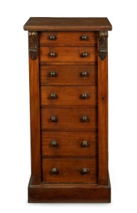 An antique English mahogany Wellington chest of seven graduated drawers with carved corbel decoration, bearing brass maker's plaque "W.H. TRAVERS, Endell St. & Castle St. Long Acre, W.C.", 19th century, 102cm high, 49cm wide, 36cm deep.
