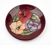 MOORCROFT floral patterned pottery dish on burgundy ground, impressed factory mark to base, ​​​​​​​12cm diameter.