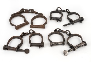 Group of three reproduction convict handcuffs with keys and a pair of leg irons, late 20th century, (4 items), the leg irons 40cm long.