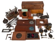 Collection remainder of magic lantern-related items, including "History of a Ship" set of five wooden slides in box, a magic lantern lens, two wooden rotary slides (defective), some wooden slide cases, and various other elements. (qty.)