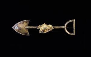 GOLD MINING BROOCH: The single shovel with diamond set blade and central nugget. Not signed and tests as 18ct yellow gold. Weight 4.37grams. 