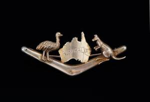 BROOCH BY WILLIS, MELBURNE: In the form of a boomerang, surmounted by a map of Australia flanked by an emu and kangaroo. 9ct yellow gold. Weight 2.63 grams.