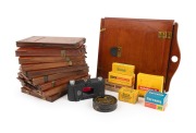 Collection remainder comprising ten mahogany double-dark slides (the largest 29.5 x 25cm), a Leitz ELDIA slide copier, five expired film products, a Trilux Exposure Meter in maker's box, and a Kodak film canister. (18 items)