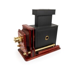 Large c. 1890s mahogany and brass MAGIC LANTERN with rack-and-pinion lens, "E. Peters Bruxelles" retailer's plate, tin chimney element, two red glass peepholes, side-opening door, slide-off rear panel, and finely carved base; later retrofitted for electri