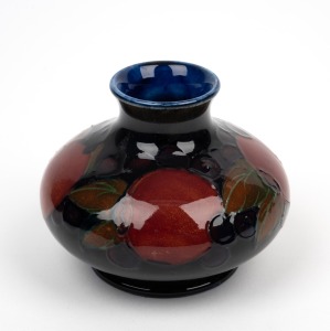 MOORCROFT "Pomegranate" English pottery miniature baluster vase on blue ground, impressed "Moorcroft, Made In England" and with original paper label, 6.5cm high.