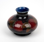 MOORCROFT "Pomegranate" English pottery miniature baluster vase on blue ground, impressed "Moorcroft, Made In England" and with original paper label, 6.5cm high. - 2