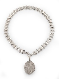 An antique engraved sterling silver locket and chain, 19th century, the locket 5cm high overall including bow, the chain 40cm long overall, 37 grams total.