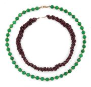 A polished garnet bead necklace with gold clasp; together with a jade coloured bead necklace with gilt metal clasp, (2 items), 48cm and 36cm long.