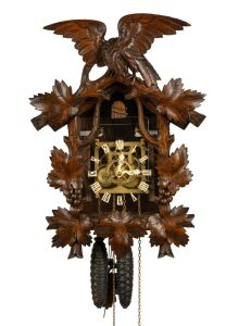 An antique German Black Forest cuckoo wall clock in carved linden adorned with vine leaf decoration and spread eagle finial, later fitted transparent dial plate displaying the fretted brass plate 30 hour movement, cuckoo and bellows. Fancy carved bone hands and Roman numerals, circa 1900, 50cm high, 35cm wide.