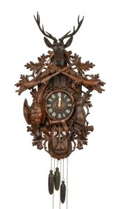 An impressive German Black Forest musical cuckoo wall clock, with dramatically carved linden wood case depicting game hunt animals, hunting horn and rifles, carved bone hands and Roman numerals, three weight movement with gong strike, cuckoo and pin barrel musical movement on the hour, circa 1890, the case 105cm high, 64cm wide.