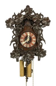 An antique German Black Forest cuckoo wall clock in ebonised linden wood case with grape vine and fruit carved decoration and two carved cuckoos, fretted carved bone hands with Roman numerals, 30-hour wood plate movement striking the half and hours on the gong, brass cased weights, circa 1870, the case 41cm high, 30cm wide.