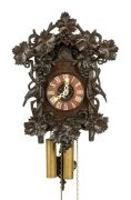 An antique German Black Forest cuckoo wall clock in ebonised linden wood case with grape vine and fruit carved decoration and two carved cuckoos, fretted carved bone hands with Roman numerals, 30-hour wood plate movement striking the half and hours on the