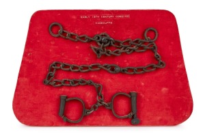 HIATT antique handcuffs and key with attached chain, mounted on red velvet display board, 19th century.