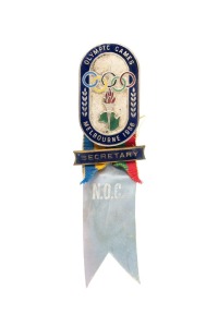 OFFICIAL BADGE - SPORTS & TEAM OFFICIALS: Manufactured by K.G. Luke, Melbourne; dark blue enamelled border, silver background, additional blue enamelled bar marked "SECRETARY" on ribbon in Olympic colours, lower pale blue ribbon marked "N.O.C."; numbered "290" on reverse.