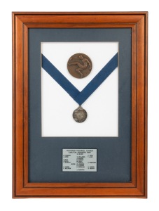 1987 CARLTON PREMIERSHIP MEDAL, obverse featuring image of stylised footballer by Andor Meszaros (1900-1972; Meszaros also known for designing the medals for the 1956 Melbourne Olympic Games); offered together with "Carlton F.C. Premiers" medallion; attractively framed and glazed, 48 x 35cm overall.
