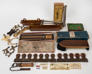 A diverse group of vintage billiards room items, including a Burroughes & Watts cue cutter, a Burman & Sons cue cutter in maker's box, a "Universal Jacio Scoreboard" in maker's box, a 19th-century ivory retailer's plate "Sold by Greer, 169, High Holborn, London", and several others. (qty.)