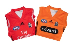 COLLINGWOOD: Two c. 2000s player-worn sleeveless training guernseys, one orange with Wizard and Adidas branding (size L), the other red with Emirates and Adidas branding.