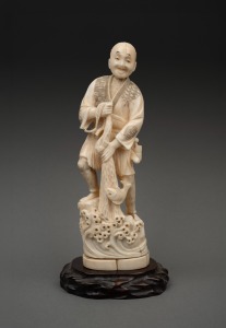 An antique Japanese marine ivory okimono of a fisherman, on later wooden base, Meiji period, 19th/20th century, ​​​​​​​21.5cm high not including base.