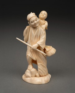 An antique Japanese carved ivory okimono of a man carrying a child, Meiji period, 19th/20th century, ​​​​​​​12.5cm high.