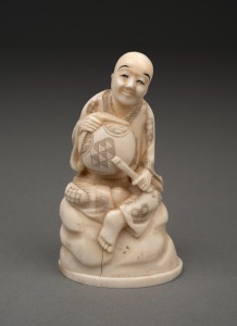 An antique Japanese carved marine ivory okimono of a seated figure, Meiji period, 19th/20th century, red seal two character mark to base, 10.5cm high.