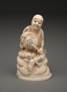 An antique Japanese carved marine ivory okimono of a seated figure, Meiji period, 19th/20th century, red seal two character mark to base, ​​​​​​​10.5cm high.