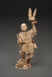 An antique Japanese carved marine ivory okimono of a cormorant fisherman, Meiji period, 19th/20th century, seal mark to base, 28cm high.