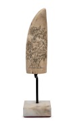 A scrimshaw whale's tooth with floral decoration, mounted on later bespoke stand, the tooth 14cm high.